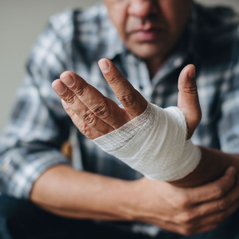 Individual with a bandaged hand and arm, wearing a plaid shirt. Injury care and recovery in focus.