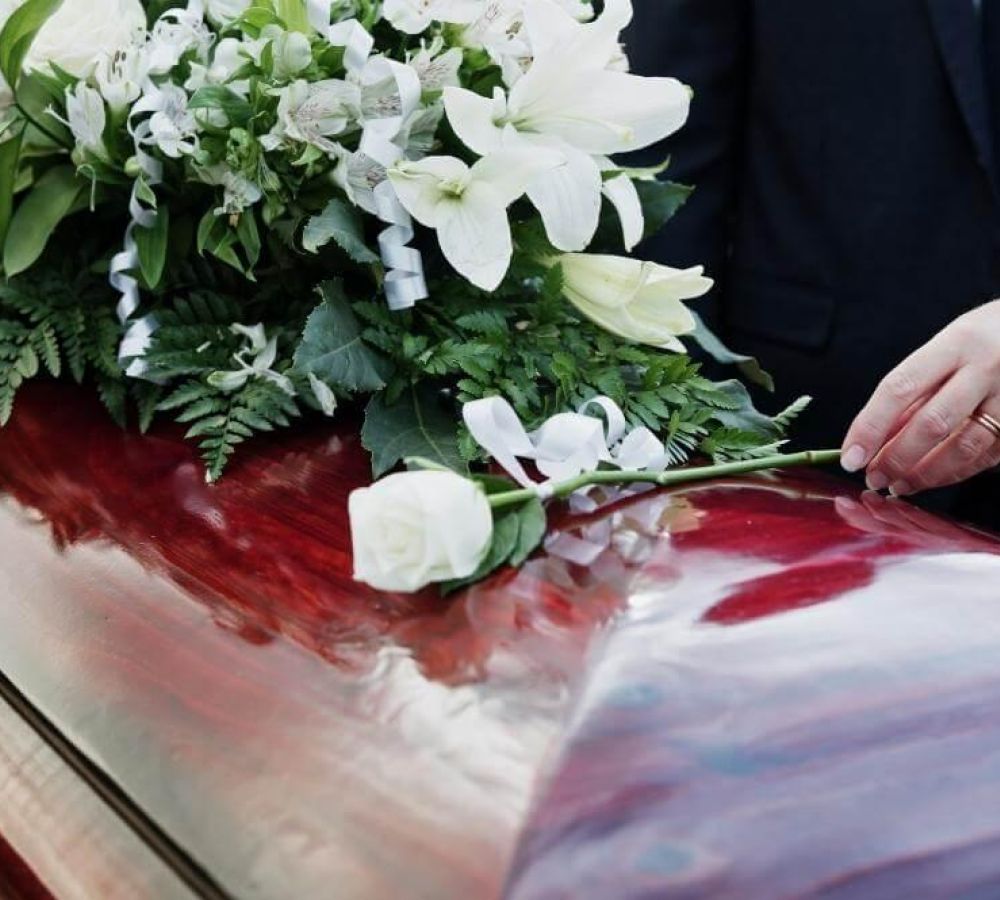 Person placing memorial flowers on a car hood