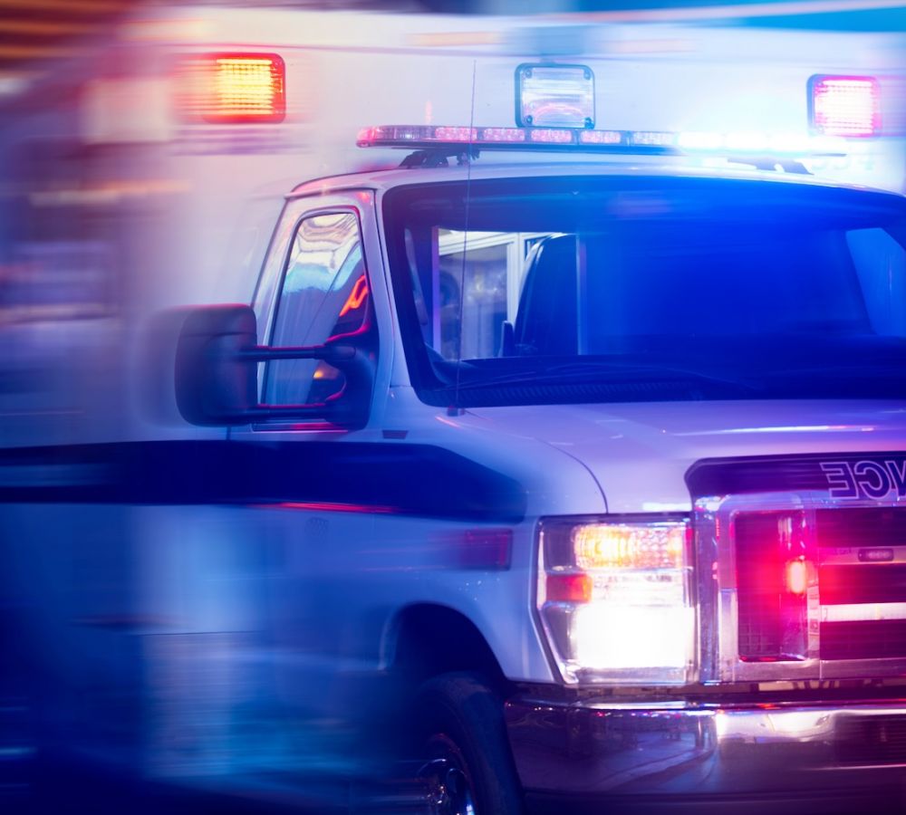 Ambulance with flashing lights in motion during nighttime emergency response.